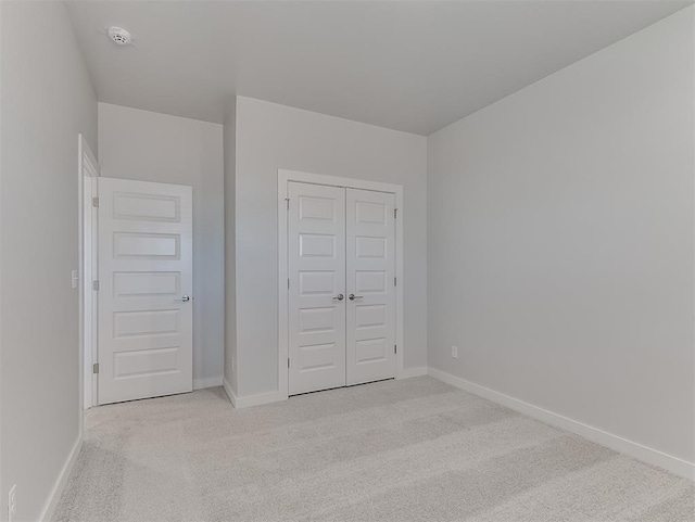 unfurnished bedroom with a closet and light colored carpet