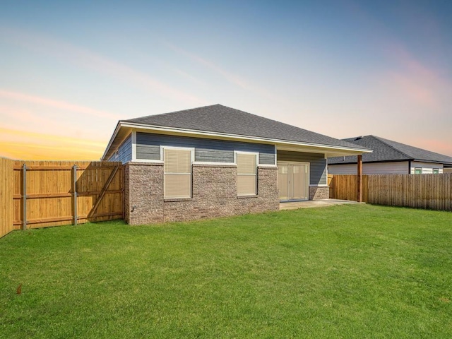 back house at dusk featuring a yard