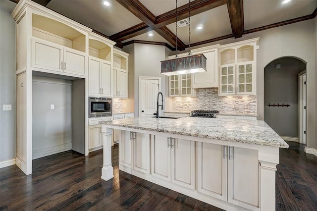 kitchen featuring a spacious island, beam ceiling, coffered ceiling, hanging light fixtures, and light stone counters