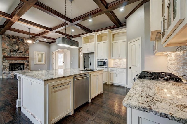 kitchen featuring a large island, stainless steel appliances, tasteful backsplash, hanging light fixtures, and light stone counters