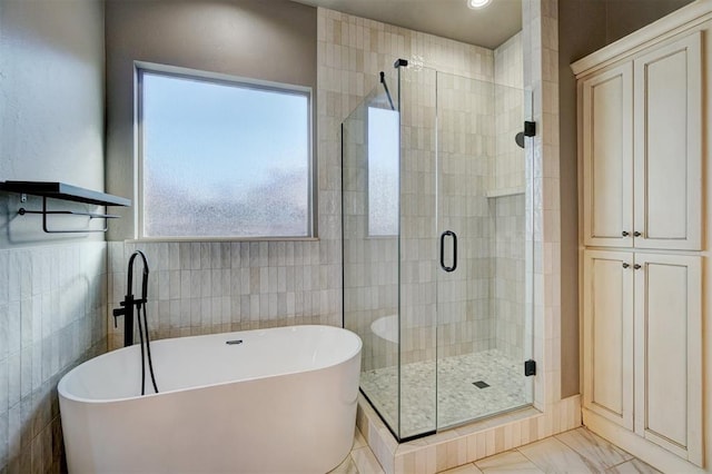 bathroom with tile walls and separate shower and tub