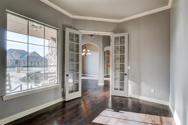 interior space with dark wood-type flooring, crown molding, french doors, and an inviting chandelier