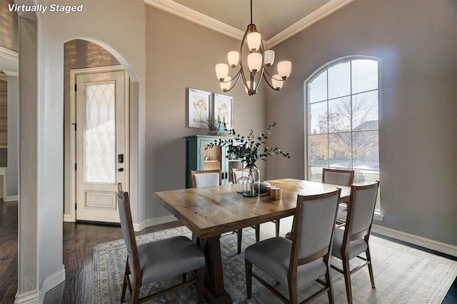 dining space featuring dark wood-type flooring, ornamental molding, and a chandelier