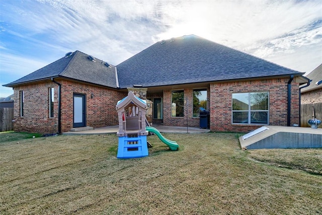 back of property with a playground, a patio area, and a yard