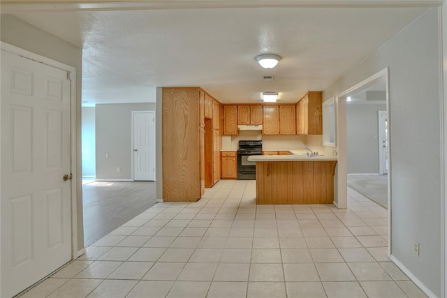 kitchen with kitchen peninsula, electric range, sink, and light tile patterned floors