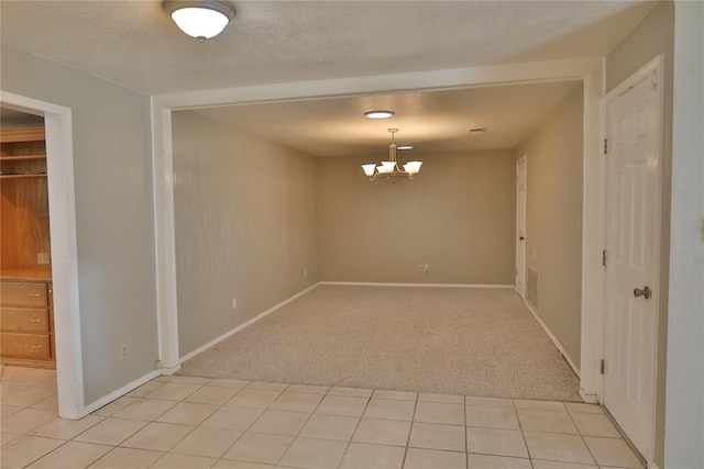 carpeted empty room featuring a chandelier