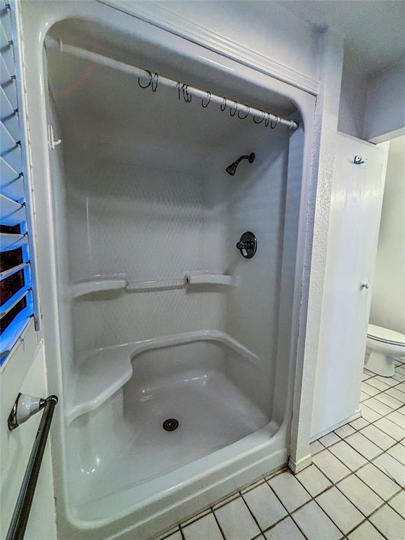 bathroom featuring toilet, tile patterned flooring, and walk in shower