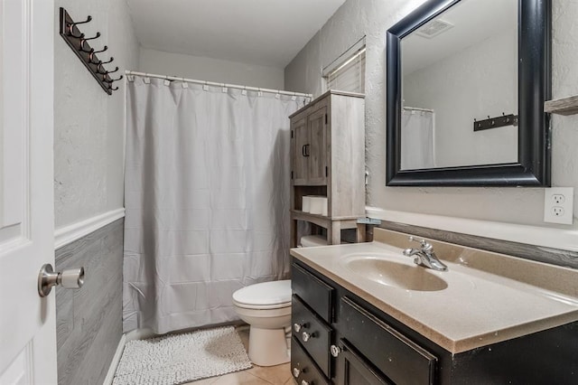 bathroom featuring tile patterned floors, vanity, tile walls, and toilet