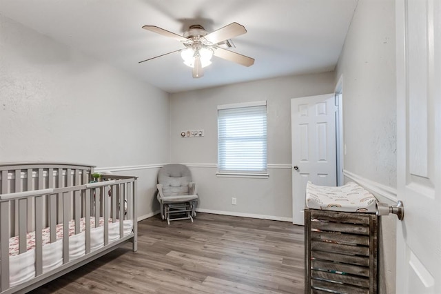 bedroom featuring ceiling fan, a nursery area, and wood-type flooring