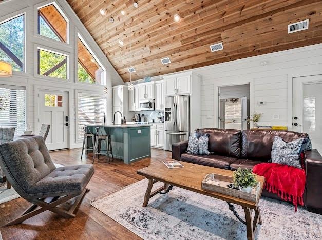 living room with wooden walls, wood ceiling, dark wood-type flooring, and high vaulted ceiling