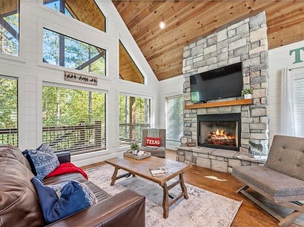 sunroom featuring wood ceiling, a stone fireplace, a healthy amount of sunlight, and lofted ceiling