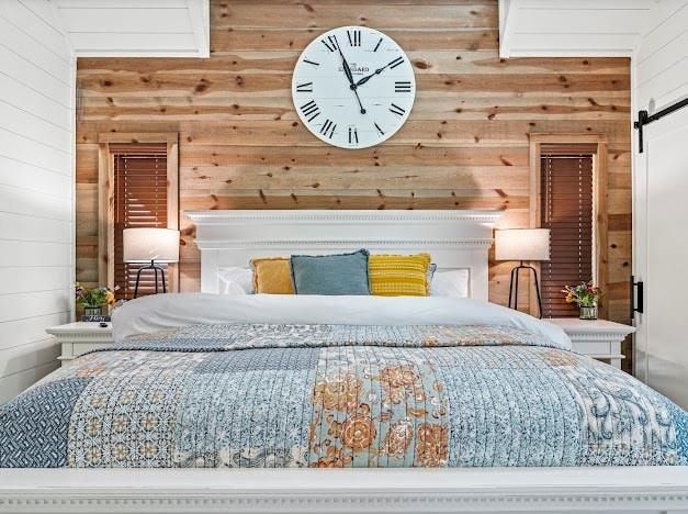 bedroom with a barn door and wooden walls