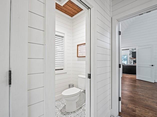 bathroom featuring lofted ceiling, wood walls, toilet, and wood-type flooring