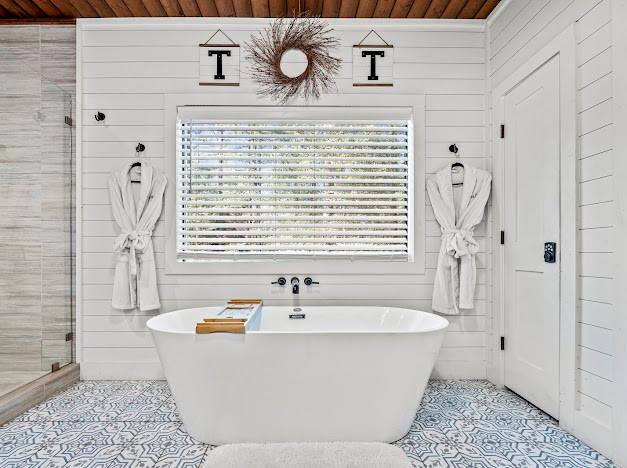 bathroom featuring independent shower and bath, wooden walls, and wood ceiling