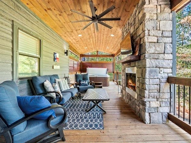 wooden deck featuring an outdoor living space with a fireplace, ceiling fan, and a hot tub