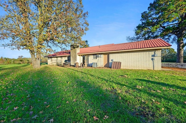 rear view of property featuring cooling unit and a yard