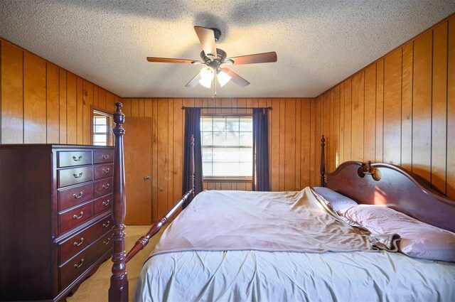 bedroom with a textured ceiling, ceiling fan, carpet floors, and wood walls