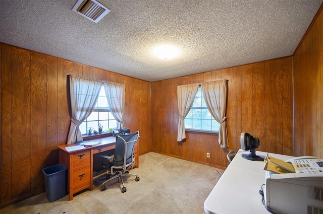 office area featuring light carpet, a healthy amount of sunlight, and wooden walls