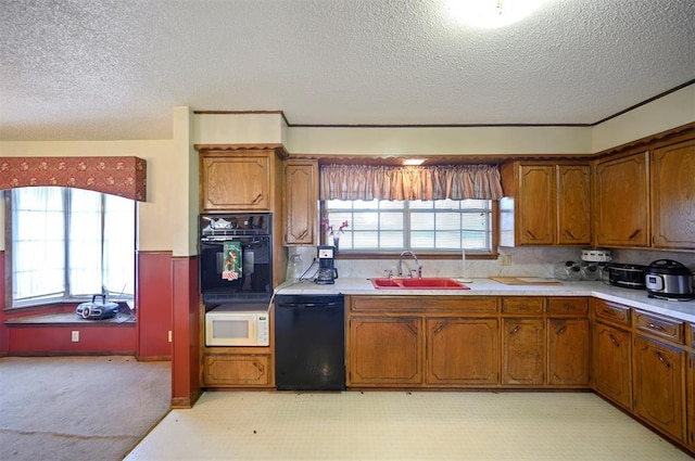 kitchen with a textured ceiling, sink, a healthy amount of sunlight, and black appliances