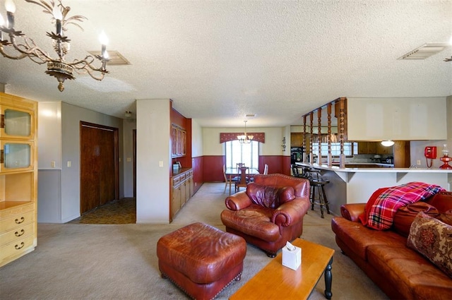 living room with a notable chandelier, light colored carpet, and a textured ceiling