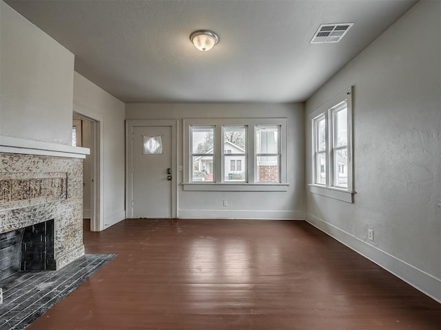 unfurnished living room with a stone fireplace and dark hardwood / wood-style flooring