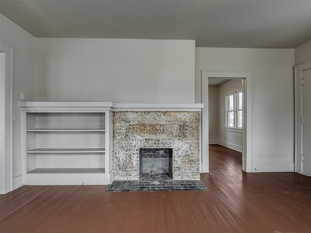 unfurnished living room with built in shelves, a fireplace, and dark hardwood / wood-style floors