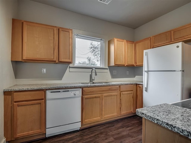 kitchen with dark hardwood / wood-style flooring, light stone countertops, sink, and white appliances