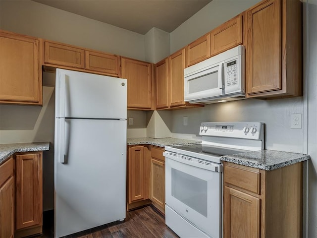 kitchen with light stone countertops, dark hardwood / wood-style flooring, and white appliances