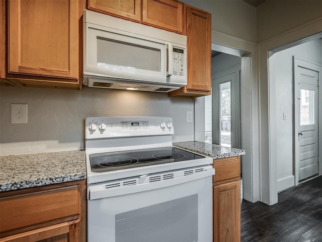 kitchen with light stone countertops, white appliances, and dark wood-type flooring