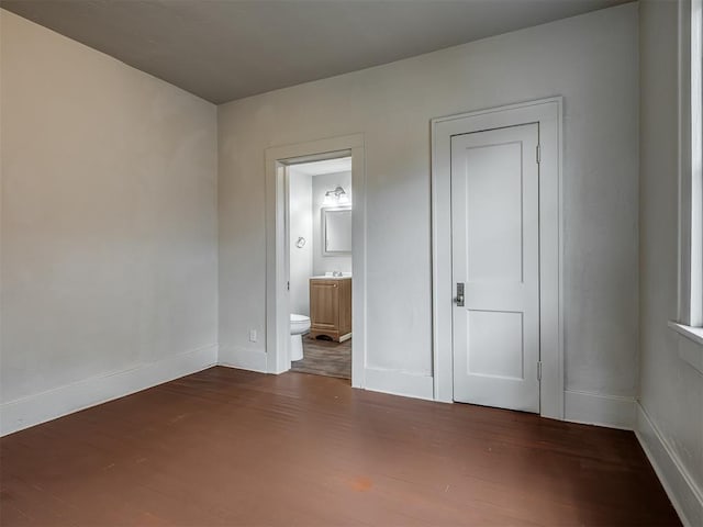 unfurnished bedroom with dark hardwood / wood-style floors and ensuite bath