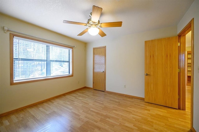 empty room with ceiling fan, a textured ceiling, and light wood-type flooring