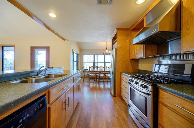 kitchen featuring hardwood / wood-style flooring, a healthy amount of sunlight, wall chimney range hood, and stainless steel appliances