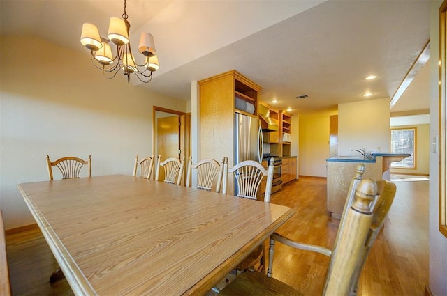 dining area featuring a chandelier, sink, and light hardwood / wood-style flooring