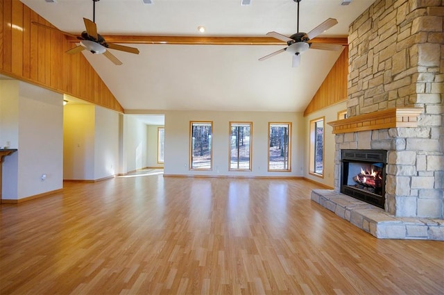 unfurnished living room with a stone fireplace, ceiling fan, high vaulted ceiling, and light hardwood / wood-style floors