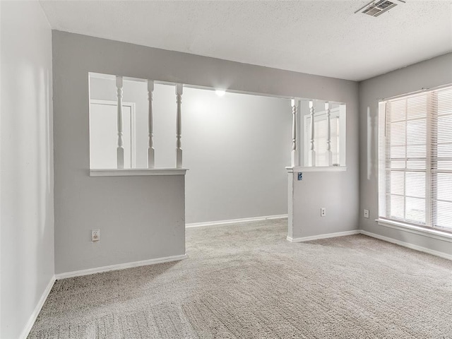 carpeted empty room with a textured ceiling and plenty of natural light