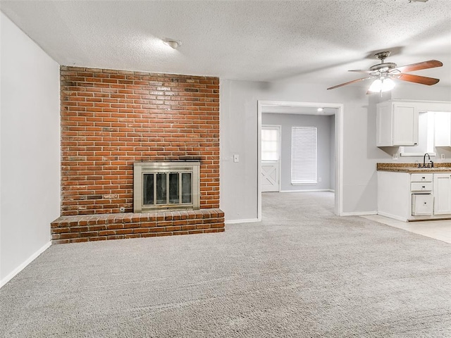 unfurnished living room with a fireplace, a textured ceiling, and light colored carpet