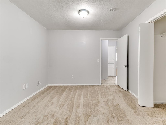 unfurnished bedroom with light carpet, a closet, and a textured ceiling