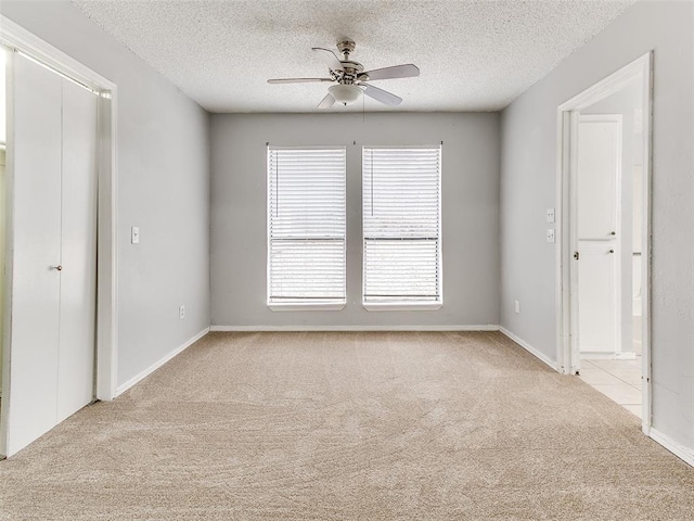 unfurnished bedroom with light carpet, a textured ceiling, and ceiling fan