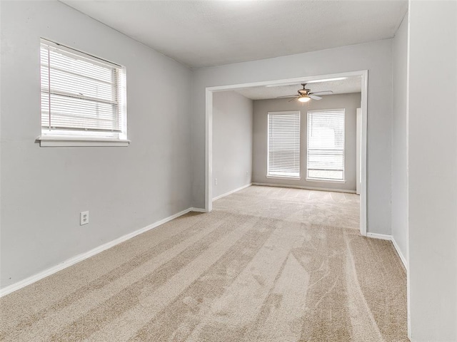 unfurnished room featuring light colored carpet, a wealth of natural light, and ceiling fan