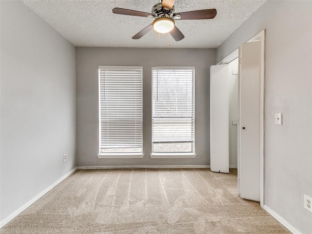 interior space with a textured ceiling, light colored carpet, and ceiling fan