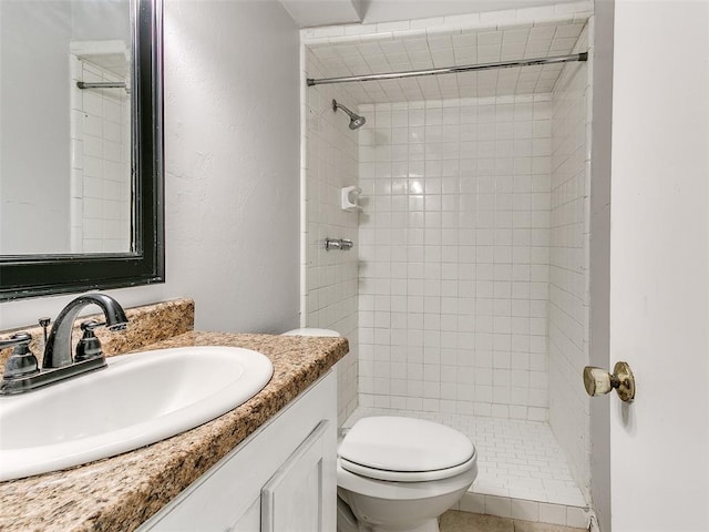 bathroom with vanity, toilet, and tiled shower