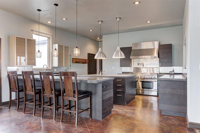 kitchen with wall chimney exhaust hood, high end stainless steel range, a center island, hanging light fixtures, and a breakfast bar area