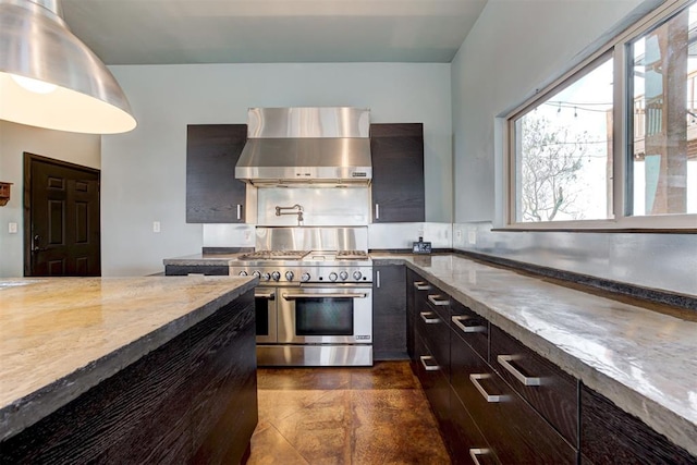 kitchen featuring wall chimney exhaust hood, range with two ovens, and light stone counters