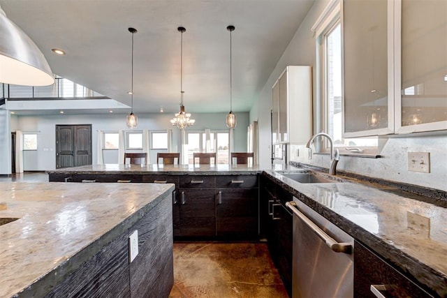 kitchen featuring stainless steel dishwasher, dark stone counters, dark brown cabinetry, sink, and a notable chandelier