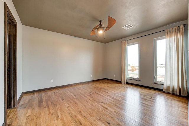 empty room featuring ceiling fan, light hardwood / wood-style floors, and a wealth of natural light