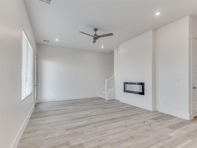 unfurnished living room with light wood-type flooring, heating unit, and ceiling fan