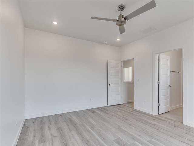 unfurnished bedroom featuring light hardwood / wood-style floors, a closet, ceiling fan, and a walk in closet