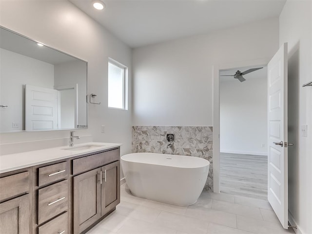 bathroom with vanity, a washtub, tile walls, and tile patterned flooring