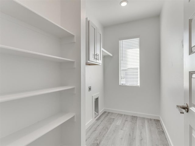 clothes washing area with cabinets, light hardwood / wood-style flooring, and electric dryer hookup