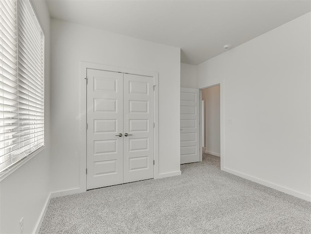 unfurnished bedroom with a closet and light colored carpet